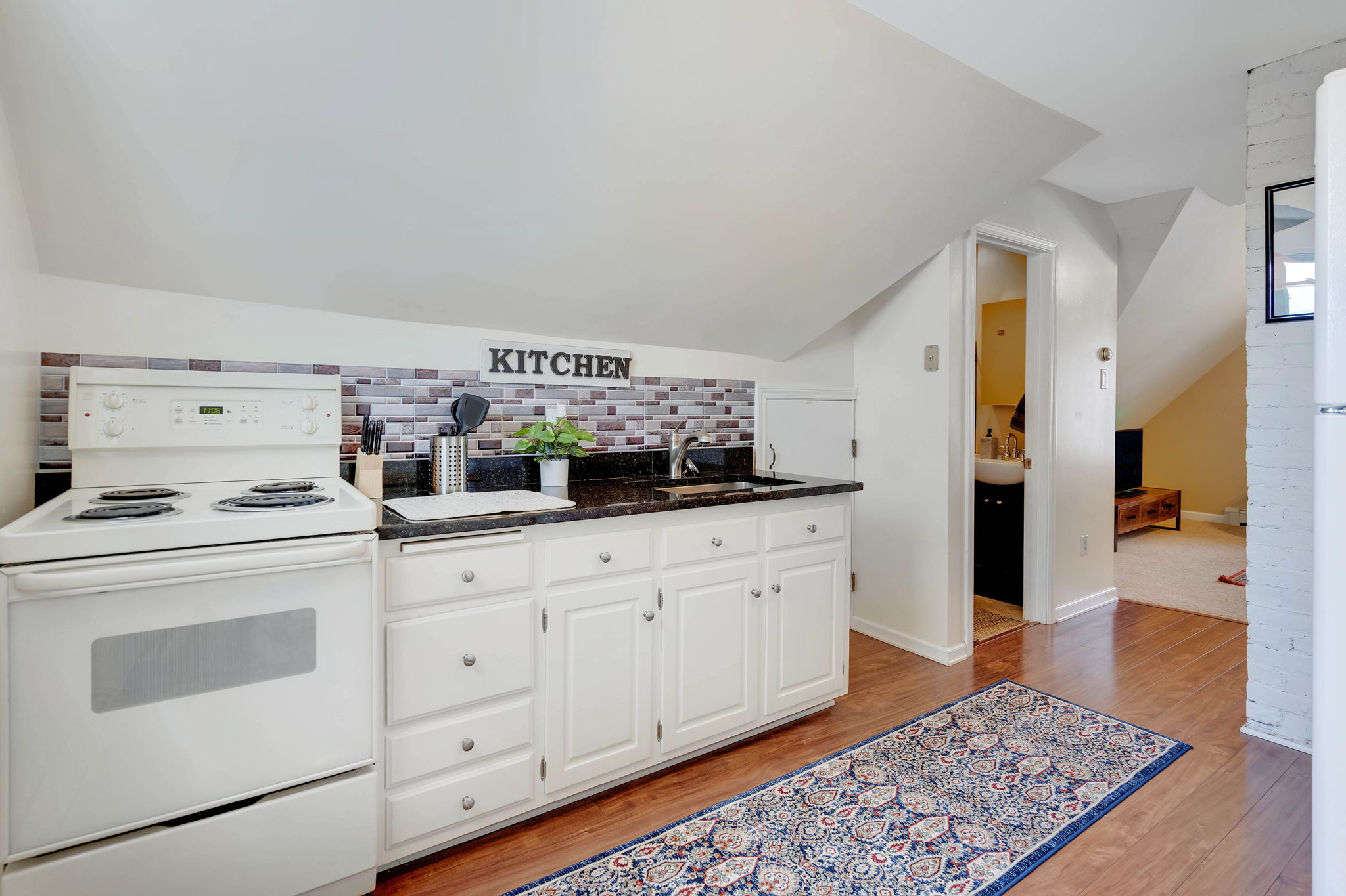 Full kitchen with white cabinetry and brick backsplash